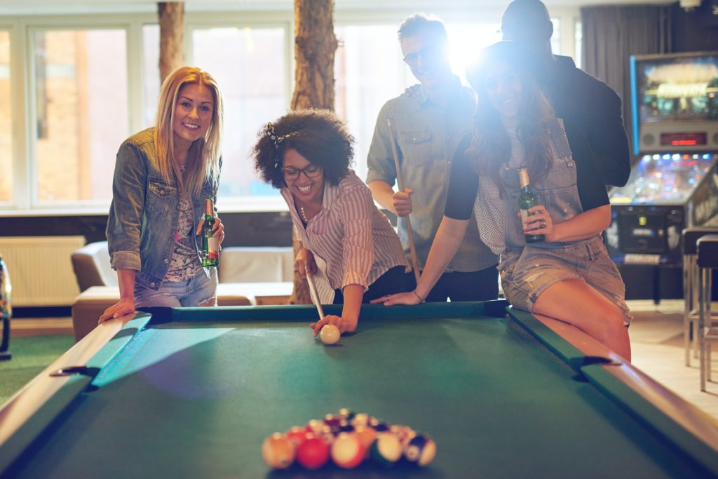 Multiracial friends playing arcade game at amusement park
