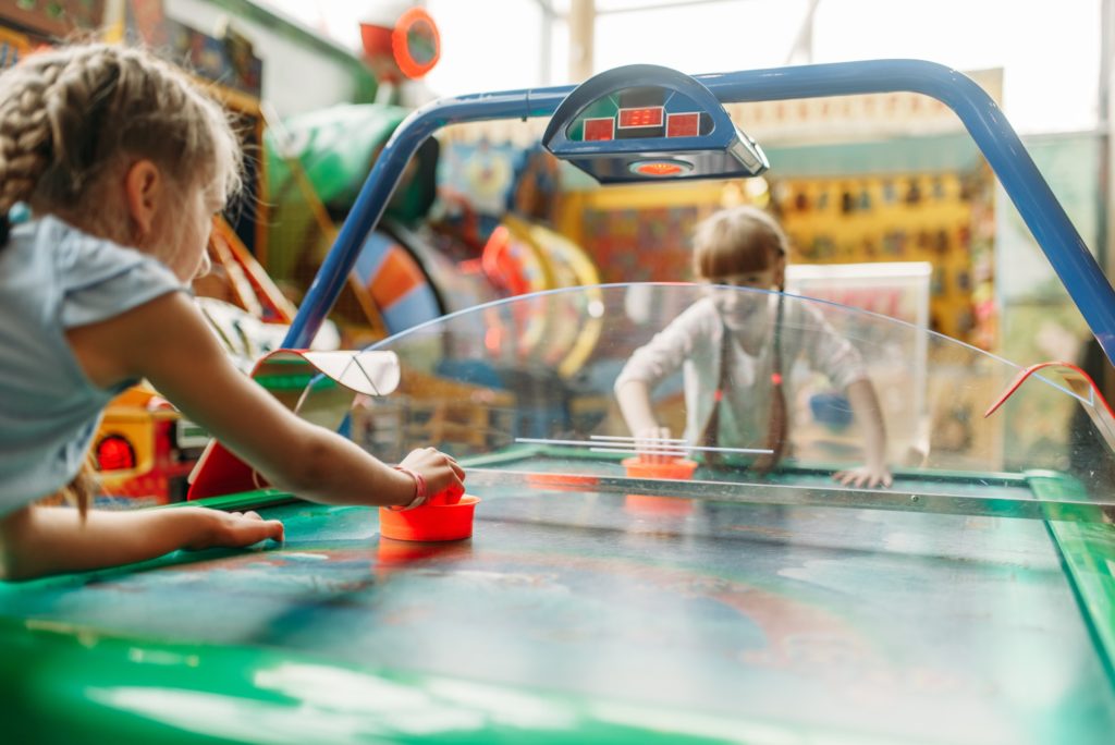 Two happy girls plays air hockey in game center